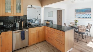 A modern kitchen with wooden cabinets, a central island, and a dining area with a table and chairs. - Single-family PB house, 1 Block to Beach (San Diego)