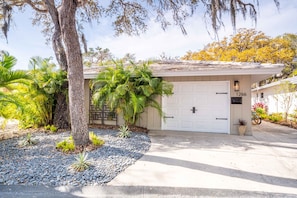 A residential house with a garage, a tree, and a well-maintained garden.