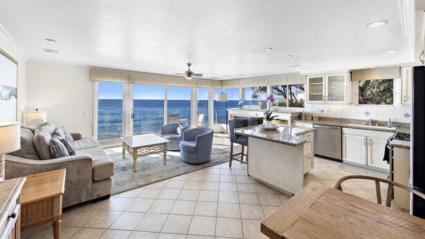 A spacious living area with a large window overlooking the sea, a kitchen with white cabinets, and a dining area with a wooden table. - 3 Unobstructed ocean view direct beach access! Oceanfront Villa with a Spectacular View (C) (Laguna Beach)