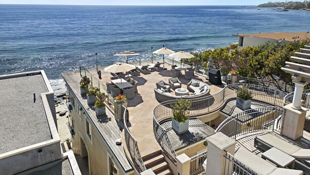 Una terraza en la azotea con mobiliario exterior, piscina y vistas al mar.