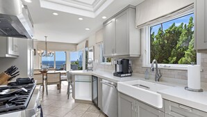 Une cuisine moderne avec vue sur l’océan, équipée d’appareils électroménagers en acier inoxydable et dotée d’une grande fenêtre.