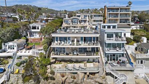 Une propriété située sur la côte, comprenant plusieurs niveaux, des espaces de détente en plein air et un rivage rocheux.