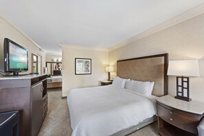 Relax in comfort with a large bed, nightstand, and dresser, featuring a television and framed artwork.
