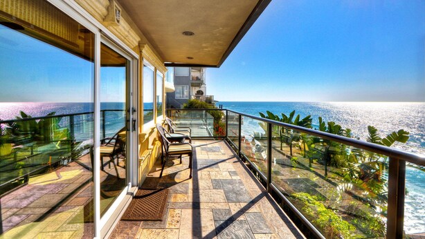 A balcony with a view of the ocean, a seating area with chairs, and a glass railing. - Breathtaking Views Savor the Sunset, Relax (Laguna Beach)