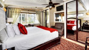 A hotel room with a large bed, a ceiling fan, a TV, and a sliding glass door leading to a balcony. - Ocean views steps to the water prime Laguna Beach 8 Villa Roma (Laguna Beach)