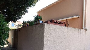 Un bâtiment doté d’une façade à motifs, d’une conduite métallique et d’un petit espace jardin agrémenté de plantes en pot.