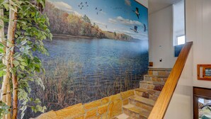 Une fresque représentant un lac avec des oiseaux, un escalier en pierre et une main courante en bois.