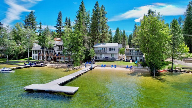 Une propriété située au bord du lac, comprenant plusieurs bâtiments, un quai et des espaces de détente en plein air.