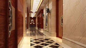 A luxurious hallway with a checkered floor, elegant lighting, and decorative wall panels. - Century Haoting Hotel (Yiyang)