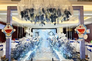 A decorated event space with a central aisle, tables on either side, and a large screen at the front. - Century Haoting Hotel (Yiyang)