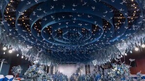 A venue with a central aisle flanked by floral arrangements and a ceiling adorned with hanging elements. - Century Haoting Hotel (Yiyang)