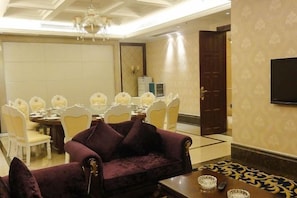 A hotel room with a dining area, a sofa, and a television. - Century Haoting Hotel (Yiyang)