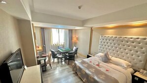 A hotel room with a bed, a desk, a chair, a television, and a window with curtains. - Century Haoting Hotel (Yiyang)