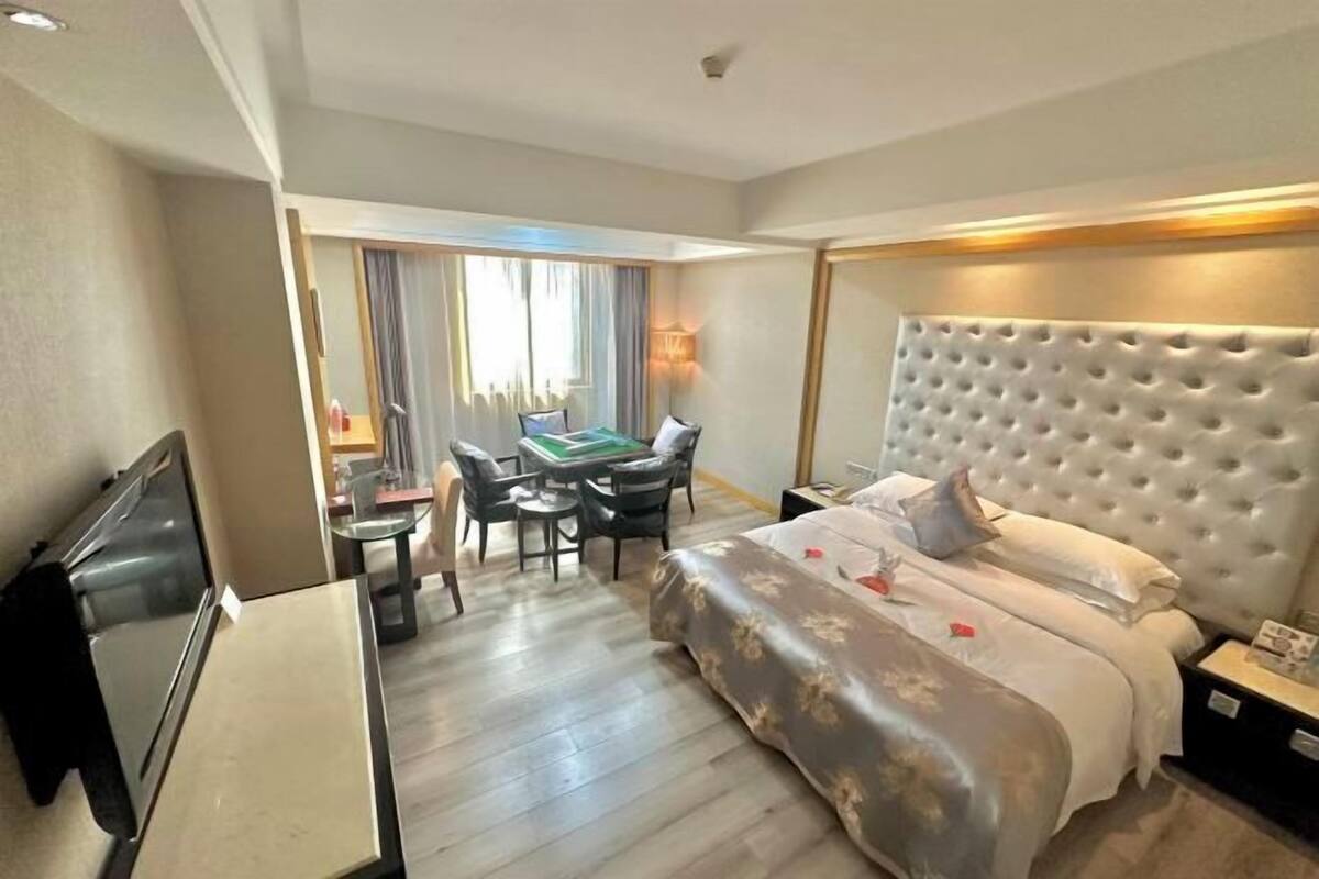 A hotel room with a bed, a desk, a chair, a television, and a window with curtains.