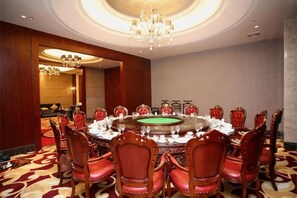 A conference room with a round table, red upholstered chairs, and a chandelier. - Century Haoting Hotel (Yiyang)