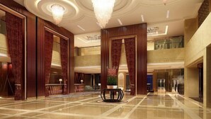 A spacious lobby with a polished marble floor, large wooden panels, and a central round table with a potted plant. - Century Haoting Hotel (Yiyang)