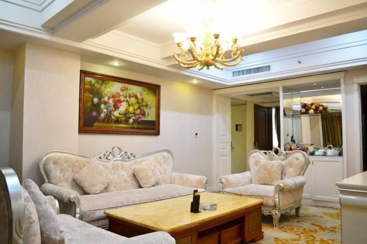 A living room with a sofa, armchairs, a coffee table, and a chandelier.
