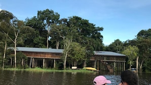 A wooden structure with a metal roof, surrounded by water and trees. - Reserva Natural Yavary Tucano (Leticia)
