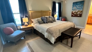 A bedroom with a bed, bedside tables, a chair, a bench, a rug, and a painting on the wall. - Rare find in Historic Orange Blossom 3/2 with golf cart (Lady Lake)