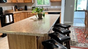 A kitchen with wooden cabinets, a granite countertop, and a central island with bar stools. - Rare find in Historic Orange Blossom 3/2 with golf cart (Lady Lake)