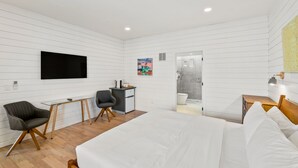 Una habitación de hotel moderna con una cama grande, un escritorio, una silla y un televisor.