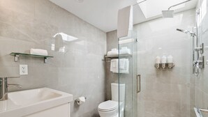 A modern bathroom with a glass-enclosed shower, a white sink, and a toilet.