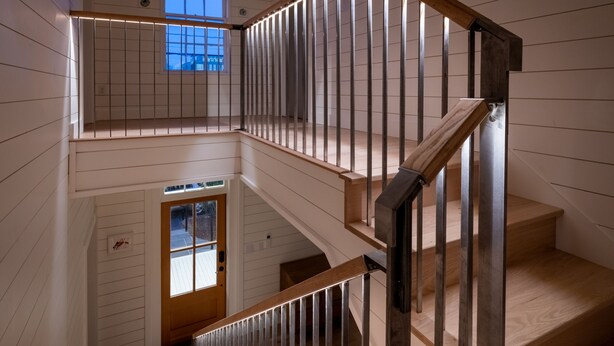 A multi-level wooden staircase with metal railings and a wooden handrail.