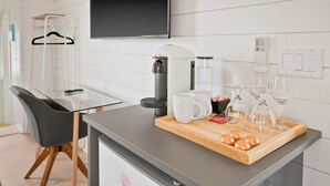 Eine moderne Küche mit einer Kaffeemaschine, einem Glastisch und einer Tablett mit Gläsern und einer Flasche.