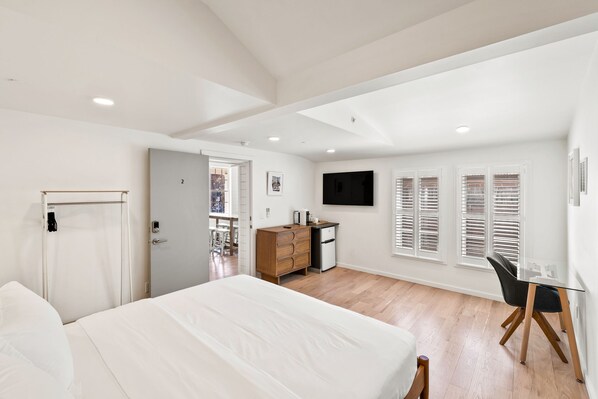 A bedroom with a bed, a desk, a dresser, and a TV on the wall. - Entire 5-Room Boutique Hotel in Downtown Charlottesville (Charlottesville)