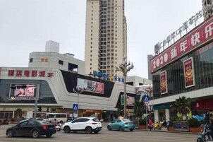 Un edificio moderno con fachada curva, grandes pantallas publicitarias digitales y un llamativo letrero rojo a la derecha.