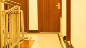 A hallway with a wooden door, a metal railing, and a tiled floor. - Longge Express Inn (Luoping)