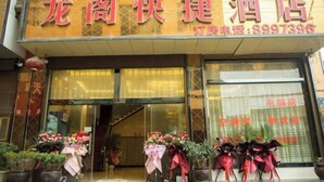 A hotel entrance with a signboard displaying the name and contact number. There are potted plants and flowers outside the entrance. - Longge Express Inn (Luoping)