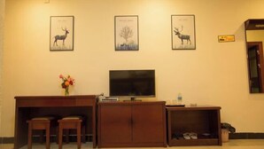 A room with a wooden desk, two chairs, a flat-screen TV, and three framed pictures on the wall. - Longge Express Inn (Luoping)