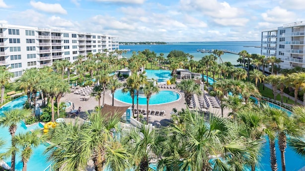 Un resort con diverse piscine, palme e vista sull'oceano.