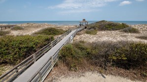A wooden boardwalk leading to a small pavilion on a sandy beach with dunes and sparse vegetation. - Ocean Views, Den, Community Pools, Close to Beach access, 103, Brigadune-Oceanfront (Corolla)