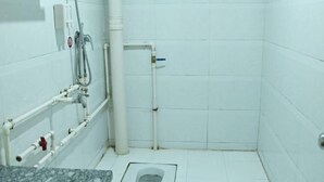 Ein kleines, sauberes Badezimmer mit weißen Fliesen, einer Toilette, einer Dusche und einem Waschbecken.