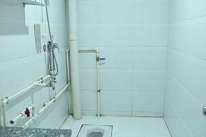 A bathroom with white tiled walls, a shower, a toilet, and a sink with a marble countertop.