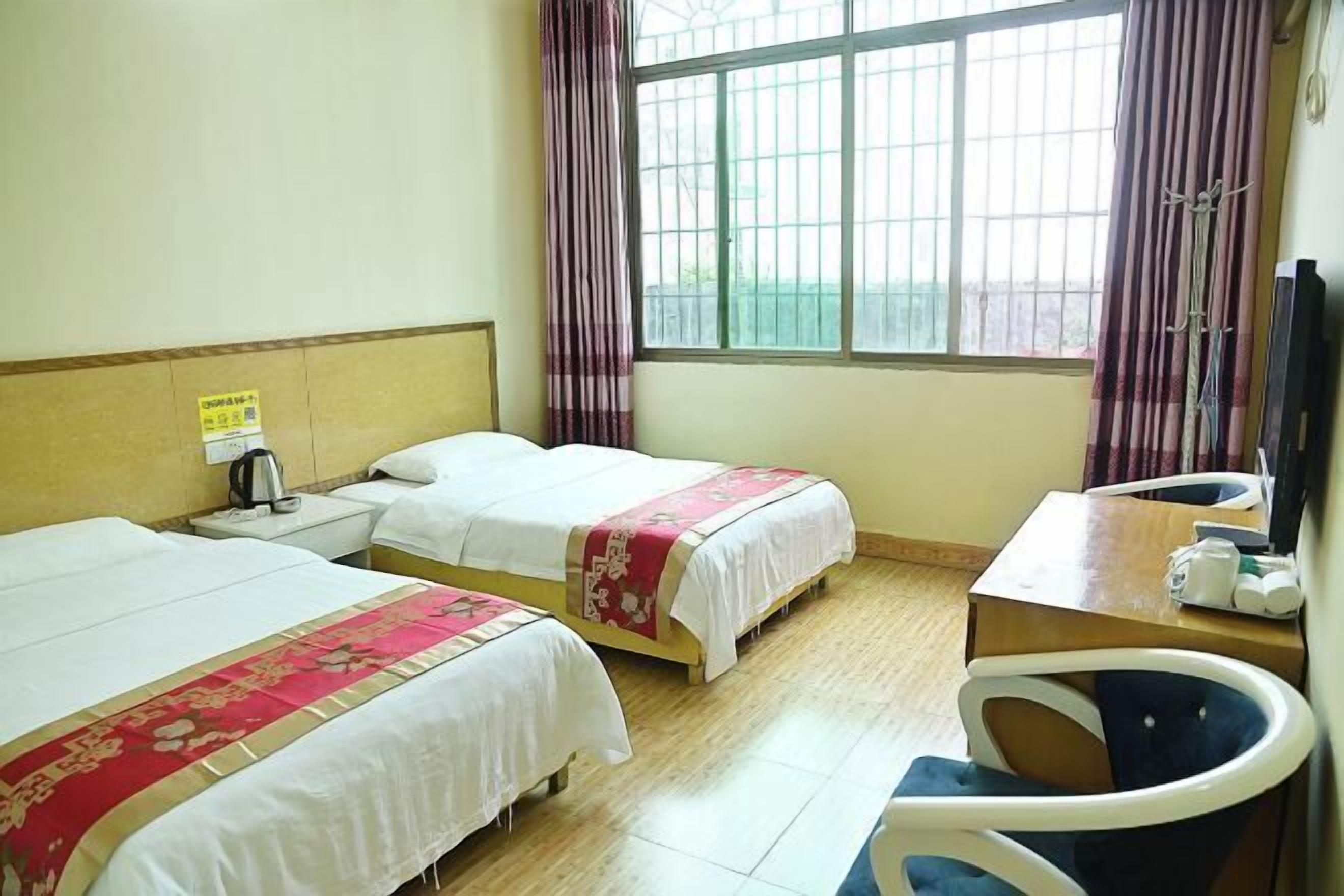 Une chambre d’hôtel avec deux lits, une petite table, une chaise et une fenêtre avec des rideaux.
