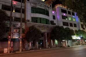 A multi-story building with a curved facade, large windows, and a prominent entrance with a sign.