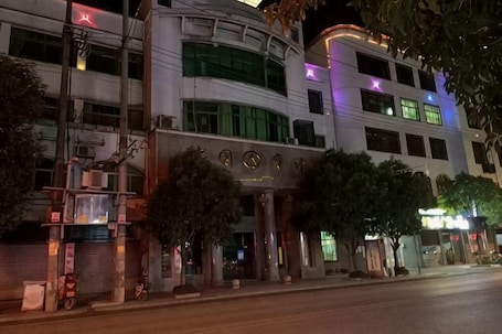 A multi-story building with a curved facade, large windows, and a prominent entrance with a sign.. Wenxin Business Hotel