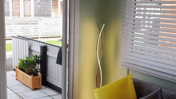 Una habitación con una puerta corrediza de vidrio que da a un patio con cerca de madera y plantas en macetas.