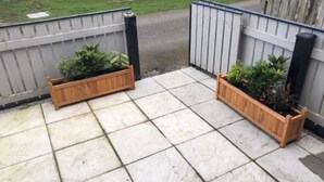 Un patio con dos macetas de madera y una reja de metal.