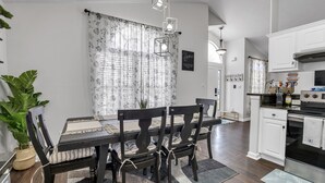 A modern kitchen with white cabinetry, a built-in oven, and a dining area with a wooden table and chairs.