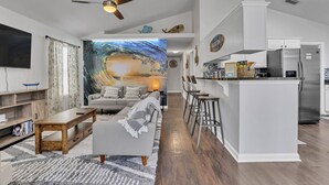 A modern living room with a large TV, a sofa, a coffee table, and a painting on the wall.