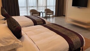 Une chambre d’hôtel avec deux lits, une télévision et un coin salon comprenant des chaises et une table.