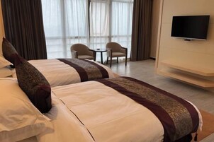Habitación de hotel con dos camas, televisión y vistas al exterior.