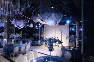 Decoração moderna com luminárias pendentes, mesas e cadeiras dispostas para refeições.