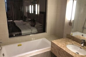 Een moderne badkamer met een grote spiegel, een badkuip en een wastafel.