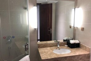 A modern bathroom with a glass shower enclosure, a beige marble sink, and a large mirror with wall-mounted lights. - Zongyang International Hotel (Zongyang)