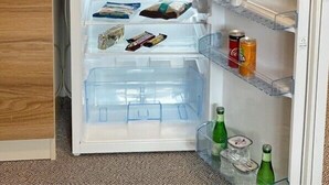 A compact refrigerator with multiple shelves, containing various food items, beverages, and a kettle. - OTEL374 (Bolu)
